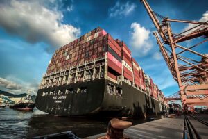 Navio porta-contêineres em porto industrial ilustra o debate sobre a redução dos insumos chineses no México, o reforço das regras de origem do T-MEC e o ajuste das cadeias de suprimentos norte-americanas com maior conteúdo regional.
