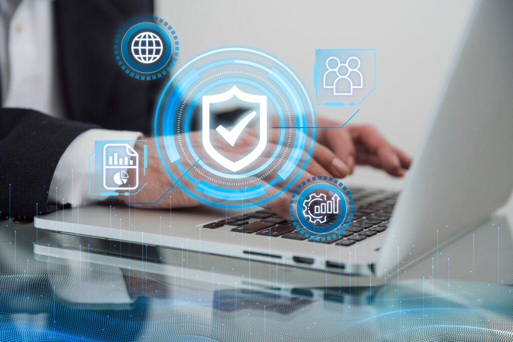 Manos de una persona con traje tecleando en una laptop, con gráficos digitales superpuestos: un escudo de seguridad central con marca de verificación, iconos de red global, análisis de datos y configuraciones. Confidencialidad y ética profesional en psicología: lo que dice la normativa mexicana.