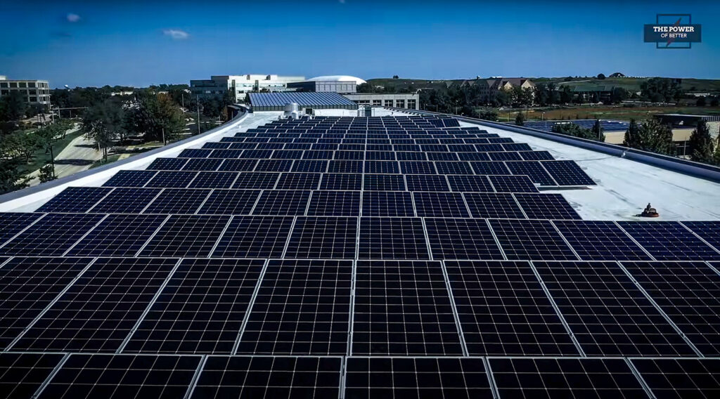 Vista aérea detallada de un extenso arreglo de paneles solares instalados sobre el techo plano y blanco de un moderno edificio comercial, mostrando eficiencia energética bajo un cielo despejado.
