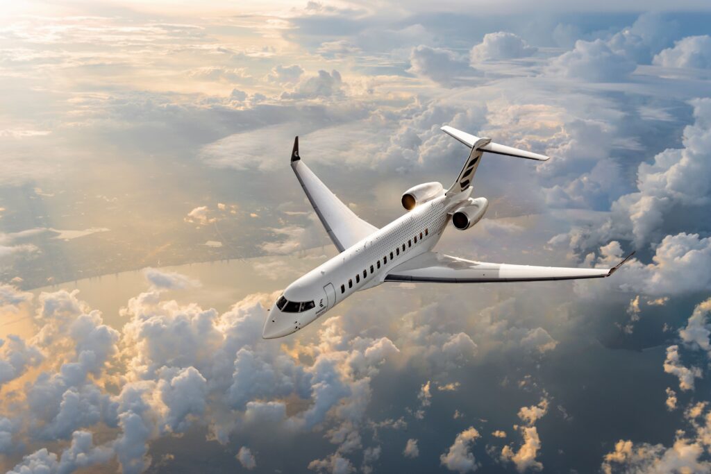 Un jet de negocios Bombardier Global 7500, con una librea blanca texturizada, vuela a gran altura sobre un mar de nubes iluminado por la luz del atardecer. Exportaciones de productos aeroespaciales de México a Estados Unidos crecen 23.9%.
