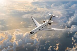 Un jet de negocios Bombardier Global 7500, con una librea blanca texturizada, vuela a gran altura sobre un mar de nubes iluminado por la luz del atardecer. Exportaciones de productos aeroespaciales de México a Estados Unidos crecen 23.9%.