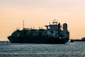 Large liquefied natural gas (LNG) carrier vessel with spherical tanks anchored at sea during sunset, highlighting the global maritime energy supply chain and seaborne gas transport infrastructure. Can AfD Reshape Global LNG Trade?